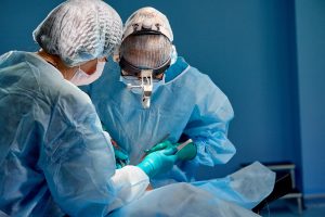 Two surgeons standing over a patient performing a cosmetic surgery procedure.